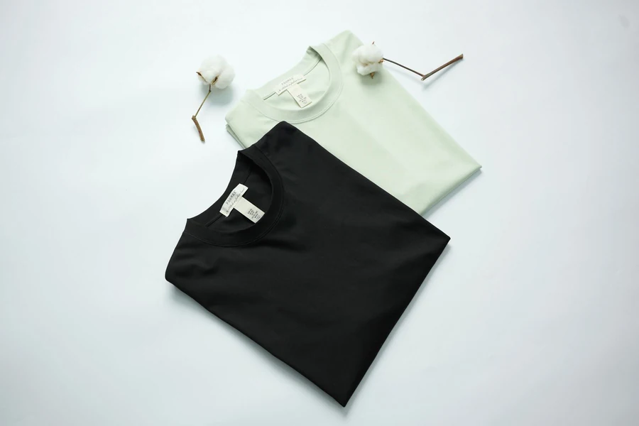 Illustrative black and sage cotton T-shirts styled on a light surface