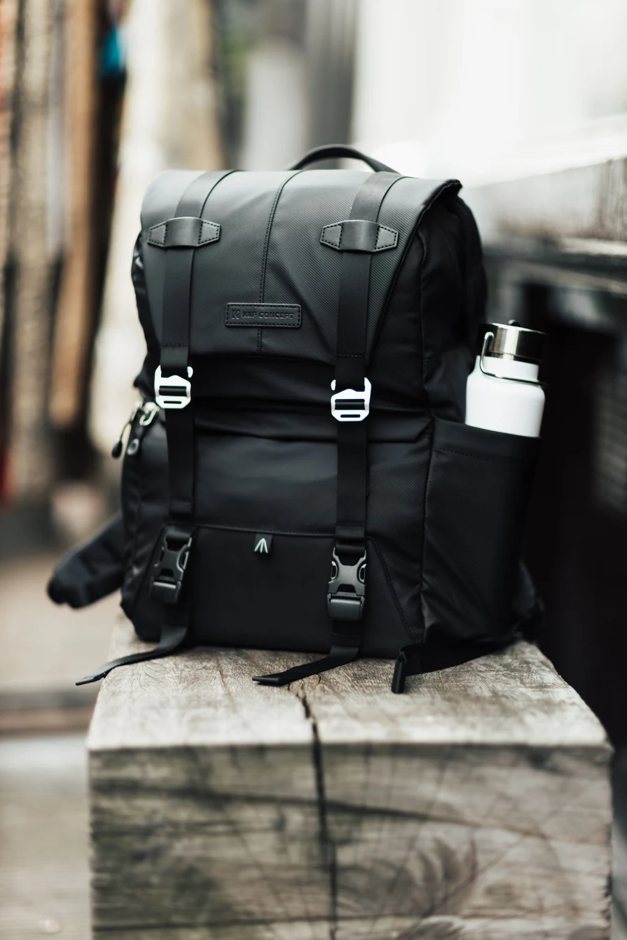 Illustrative black backpack and travel bottle on a wooden bench