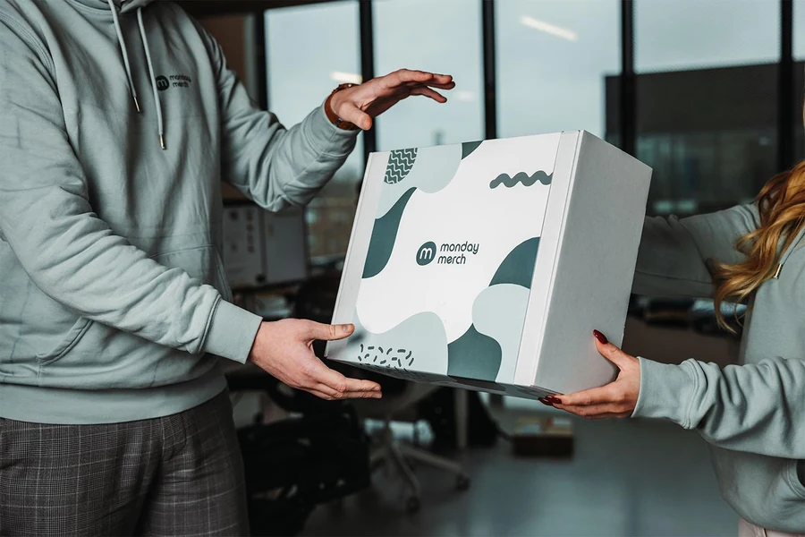 Colleagues exchanging a coordinated branded merchandise box in a modern office