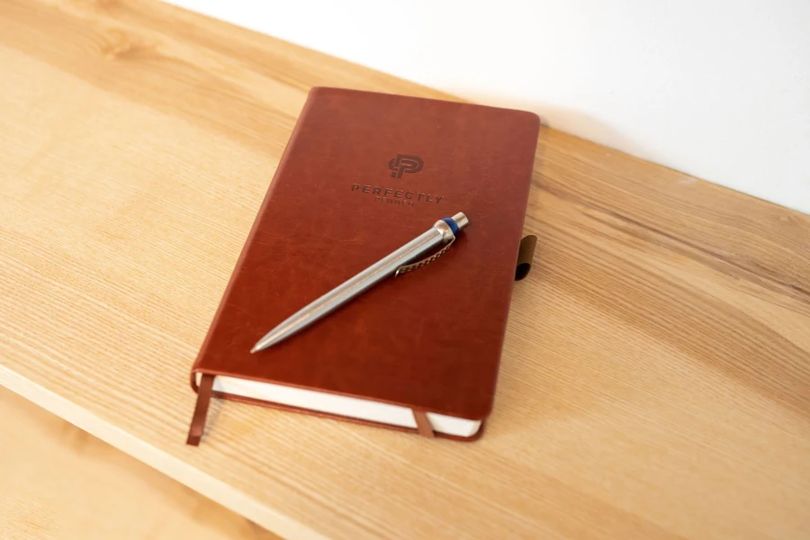 Illustrative leather notebook and pen on a wooden desk